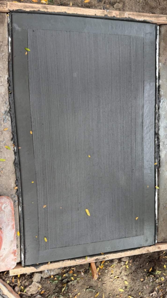 Close-up of a new concrete slab with broom finish and tooled edges set in wooden forms