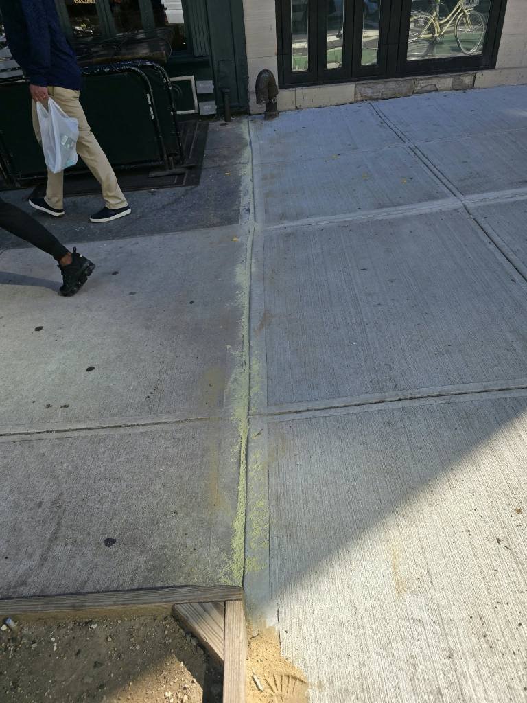Smooth old-to-new sidewalk flag transition beside a storefront, DOT violation repair in Yorkville, NYC