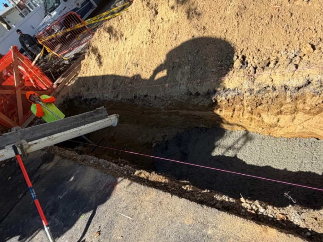 Crew pouring concrete into an excavated foundation trench, part of NYC foundation repair and underpinning work